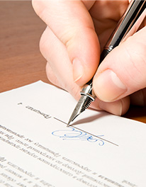Se muestra una mano firmando un documento