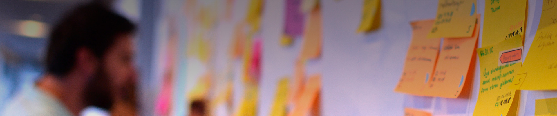 Un joven se encuentra frente a una pared repleta de papeles de colores con anotaciones